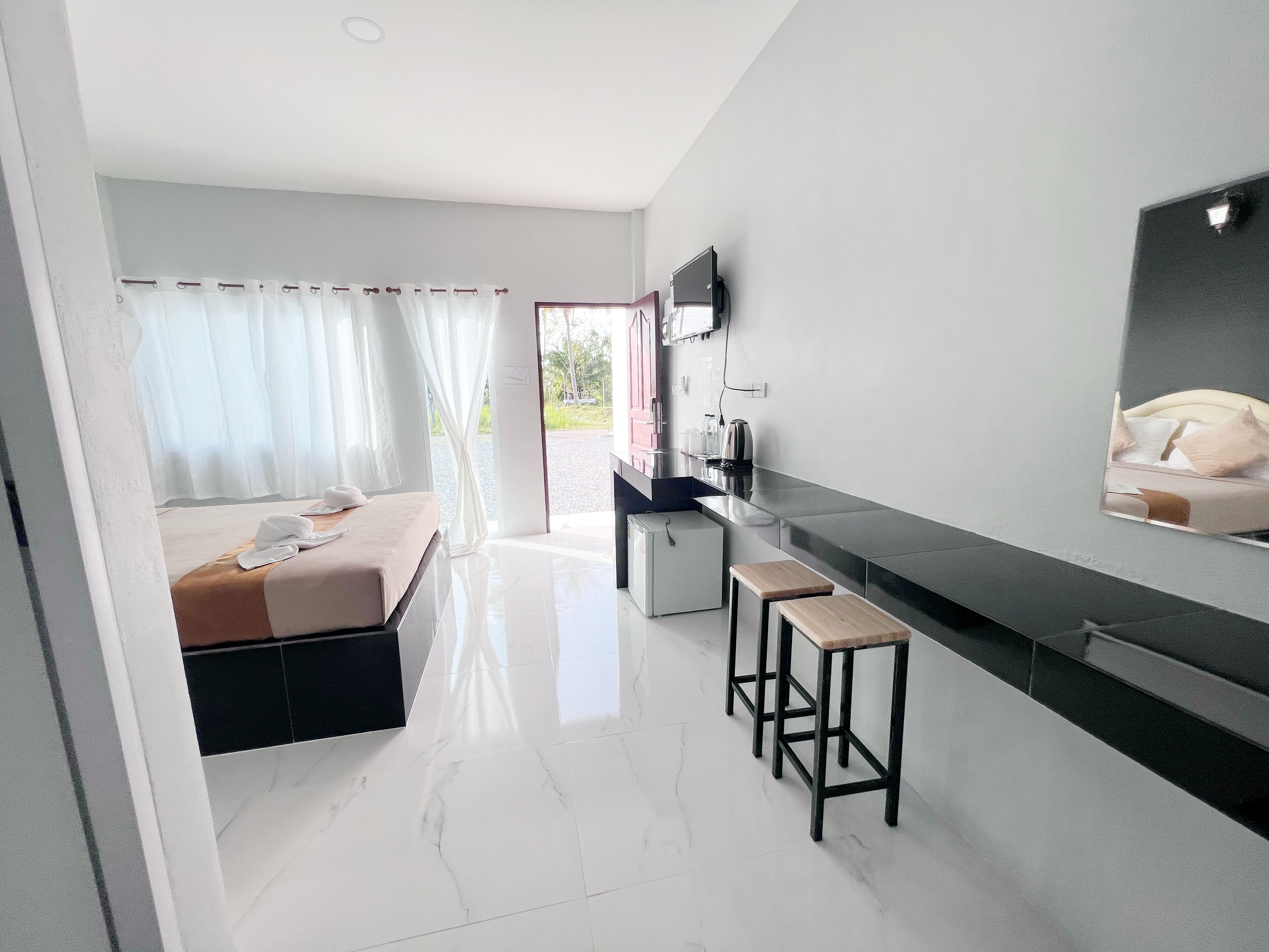 Habitación de hotel moderna con cama, una kitchenette pequeña, televisión montada en la pared y vistas al exterior.