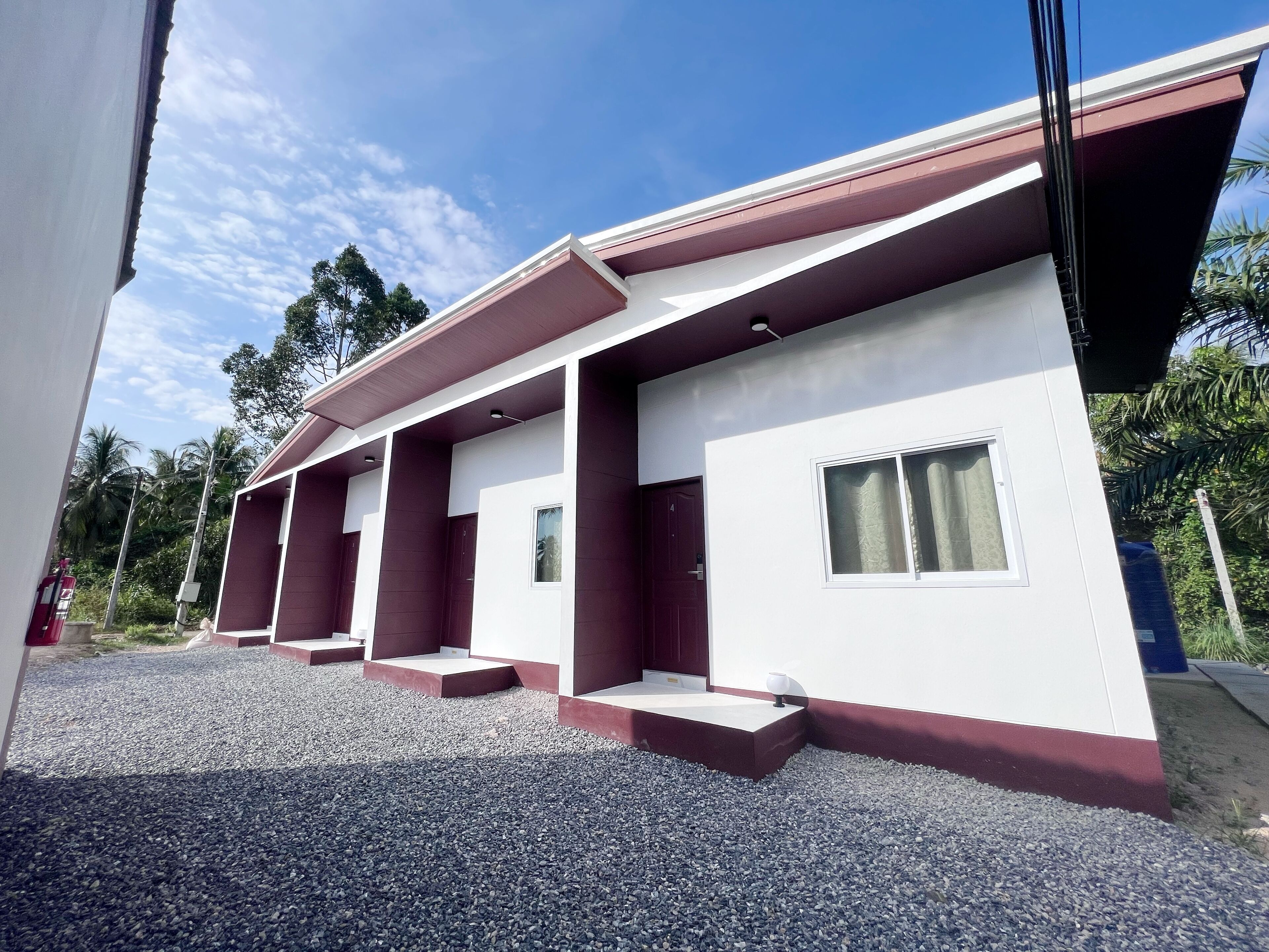 A modern building with a flat roof, multiple windows, and a gravel driveway.