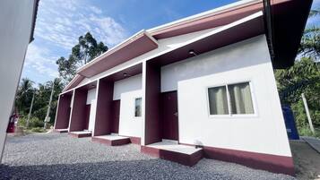 A modern building with a flat roof, multiple windows, and a gravel driveway.