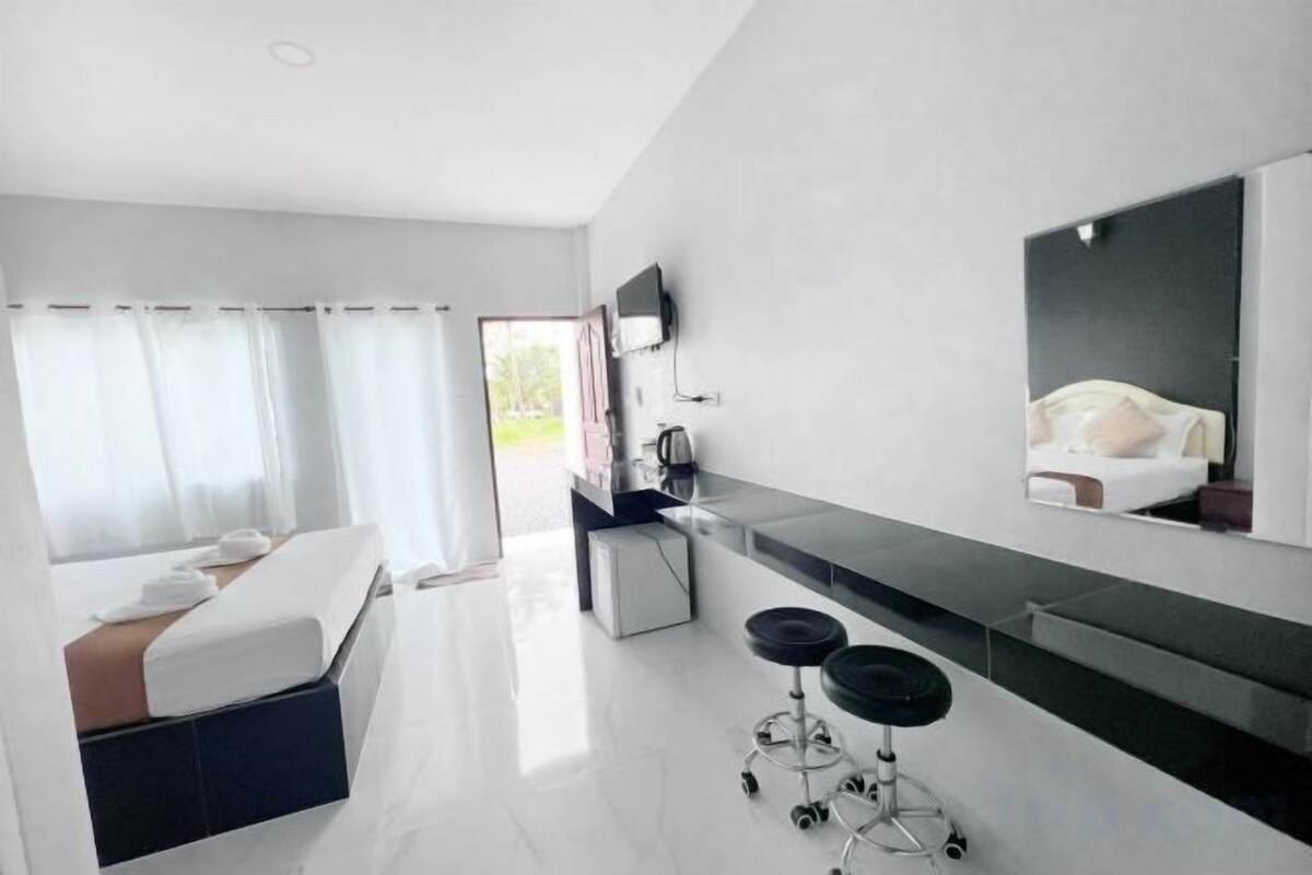 A modern hotel room with a bed, a desk, a chair, and a large mirror.