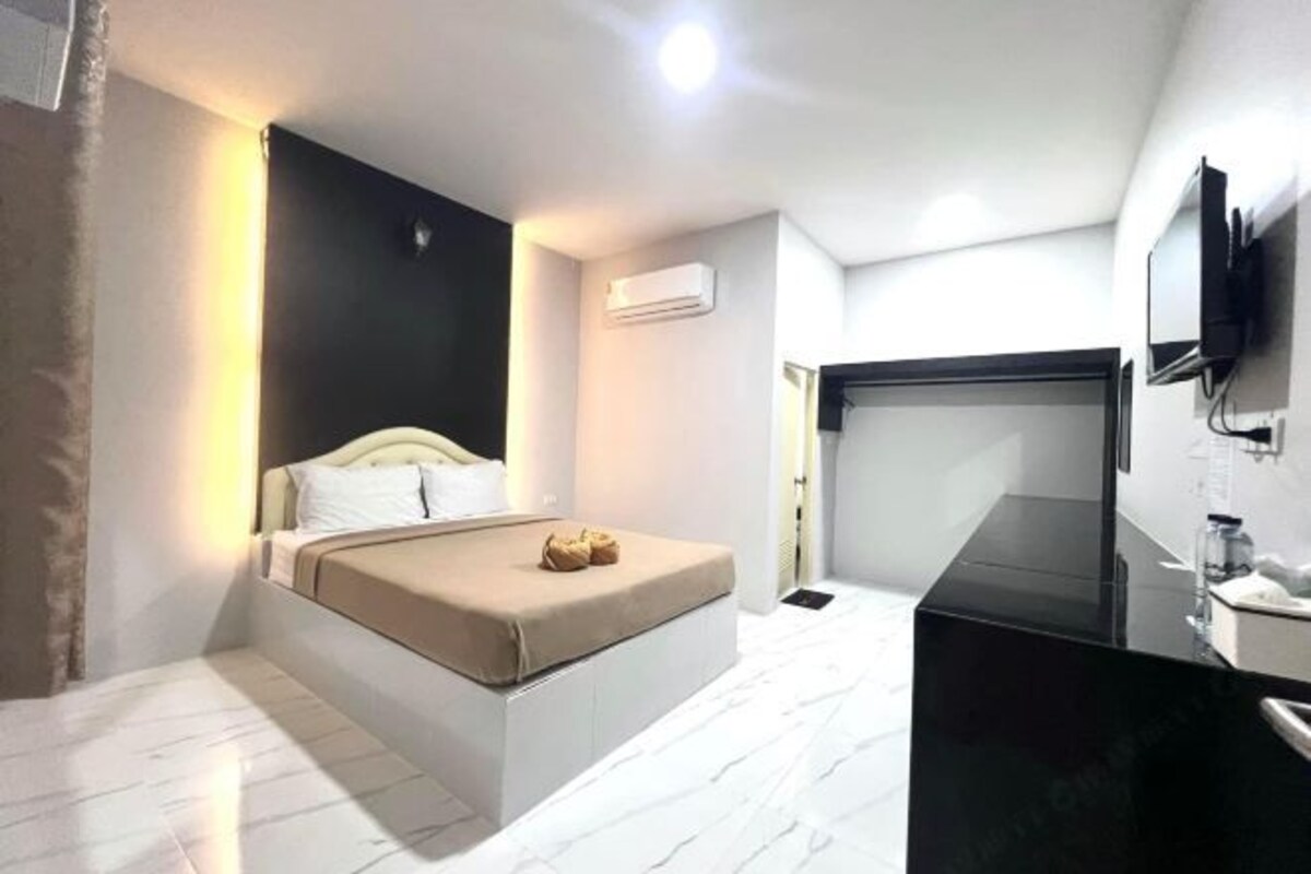 A modern bedroom with a bed, a black vanity, and a mounted TV.