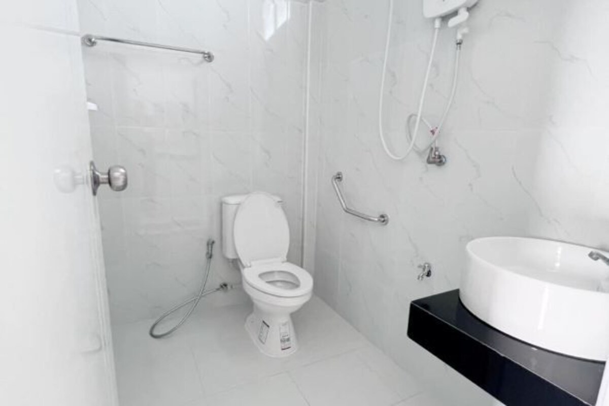 A modern bathroom with a white toilet, a black sink, and a shower.