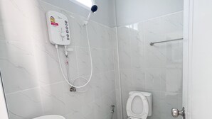 Un bany amb vàter blanc, un lavabo i una dutxera.