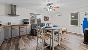 A kitchen with a built-in oven, a ceiling fan, and a dining area with a table and chairs. - Renovated Rustic Charm! (New Bern)