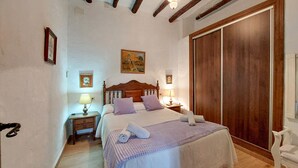 Une chambre à coucher avec un lit en bois, deux tables de chevet avec des lampes, une grande armoire et un tableau au mur.