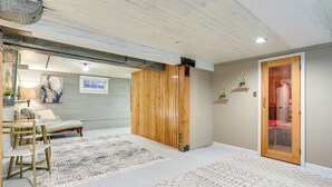 A modern living room with a wooden partition, a dining area with a table and chairs, and a patterned rug. - Quaint Studio w/ Sauna: 5 Mi to Space Needle (Seattle)