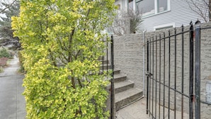 A residential building with a stone wall, a metal gate, and a concrete staircase. - Quaint Studio w/ Sauna: 5 Mi to Space Needle (Seattle)