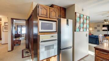 A kitchen with wooden cabinets, a microwave, an oven, and a refrigerator.