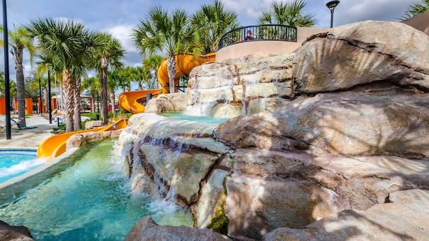 Un parc aquatique avec un toboggan aquatique, une piscine et des palmiers.