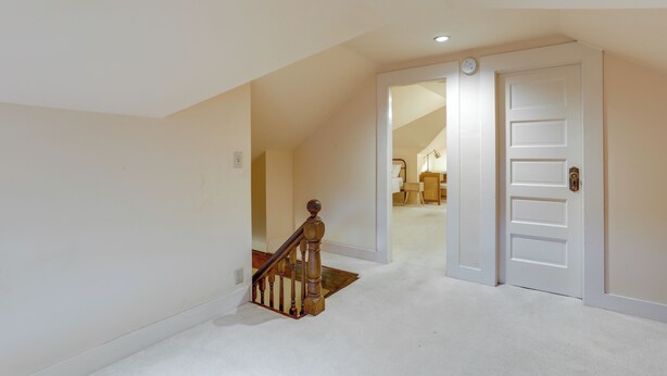 A hallway with a carpeted floor, a wooden staircase with a handrail, and a white door. - Inviting Seattle Apartment: 4 Mi to Ballard Locks (Seattle)