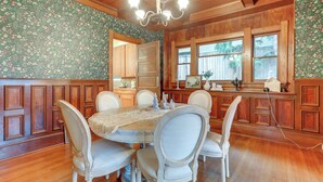 A dining room with a wooden table and chairs, surrounded by wooden paneling and floral wallpaper. - Inviting Seattle Apartment: 4 Mi to Ballard Locks (Seattle)