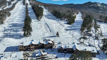 Ein Skigebiet mit mehreren Gebäuden, Skipfällen und einem verschneiten Berghang.