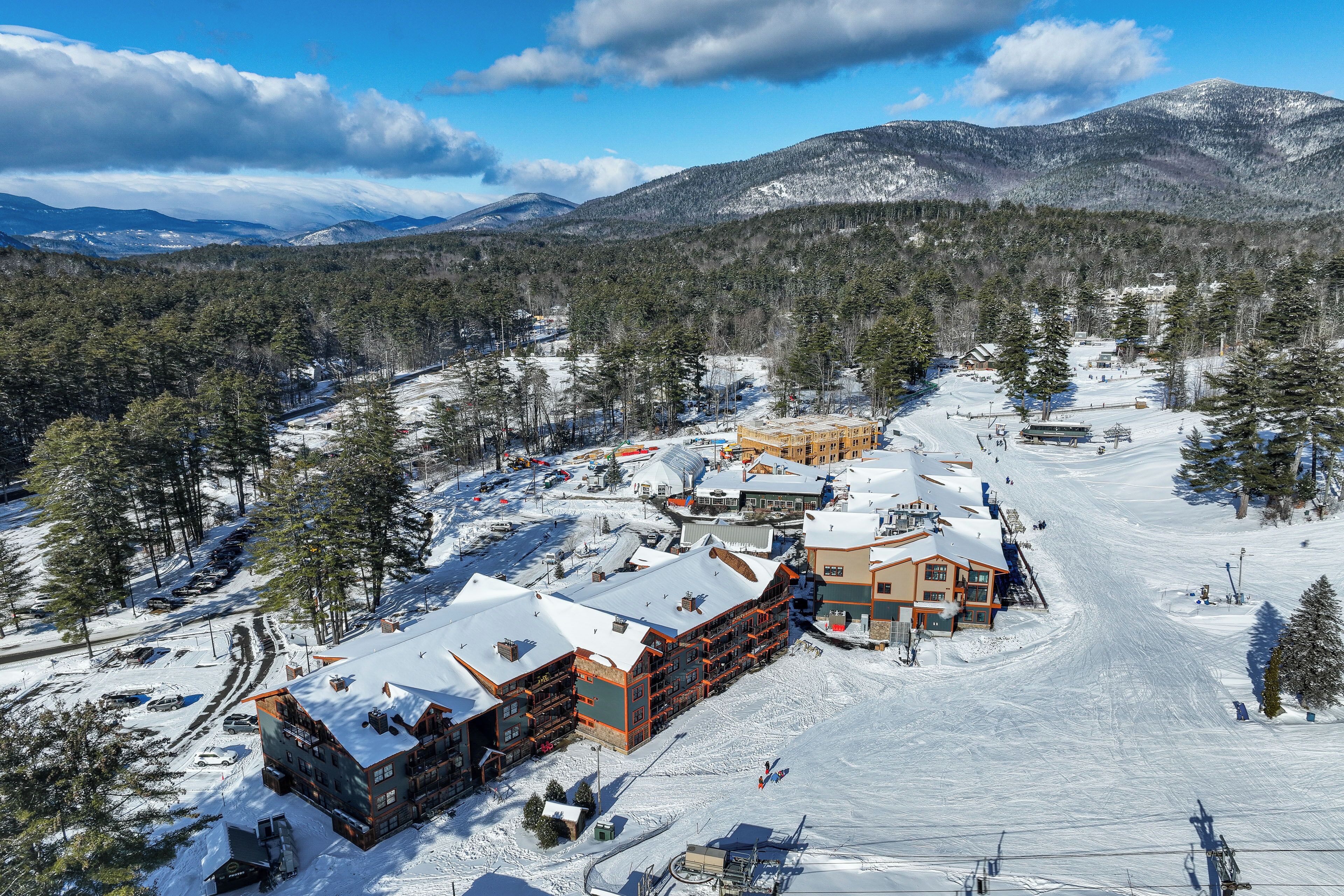 A snow-covered ski resort with multiple buildings, including a lodge with a ski lift visible.