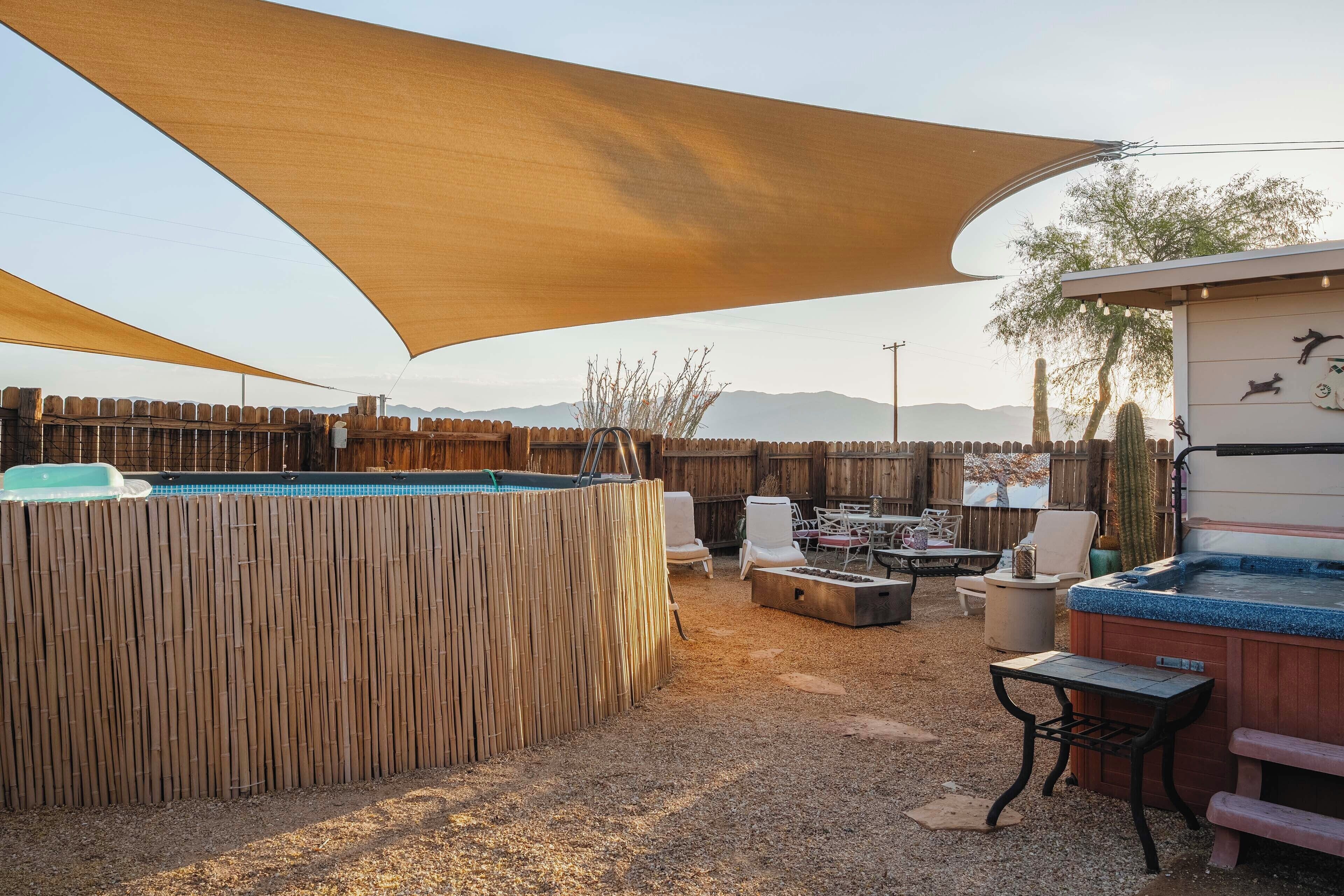 A backyard with a pool, outdoor seating, and a hot tub.