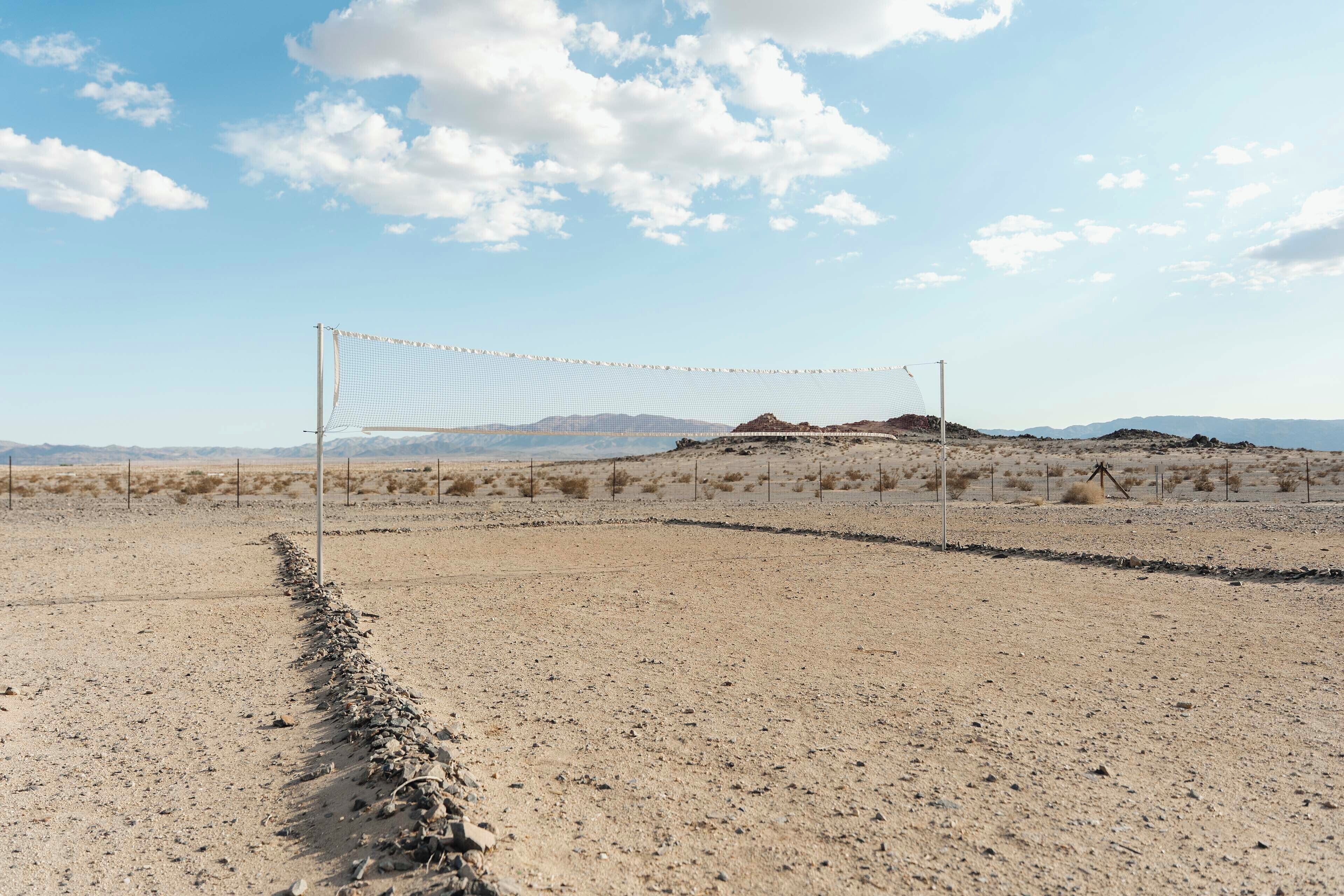 A volleyball net in a desert landscape with mountains in the background.