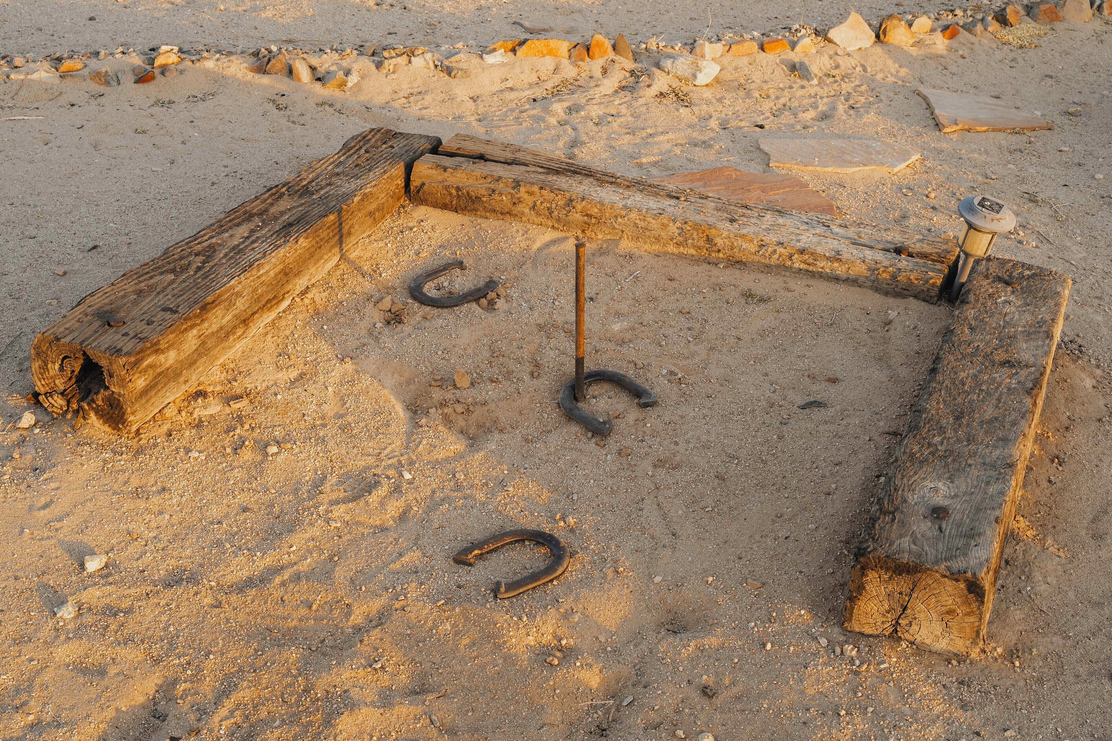 A wooden structure with metal rings on a sandy surface.