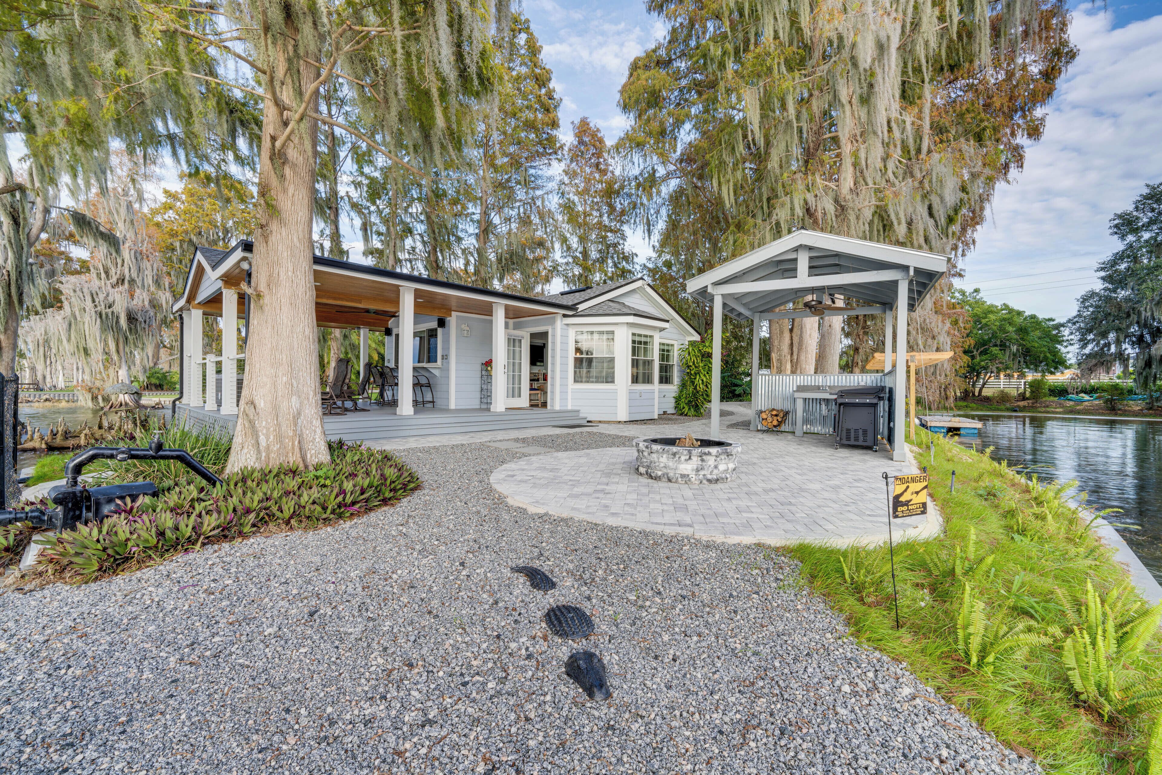 Une maison moderne dotée d’un patio couvert, d’un étang et d’un foyer extérieur.