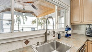 A kitchen with a stainless steel sink, wooden cabinets, and a view of the outdoors. - Hot Tub & Fire Pit: Lakefront Home on Lake Eloise (Winter Haven)