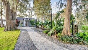 A pathway leading to a house surrounded by trees and plants. - Hot Tub & Fire Pit: Lakefront Home on Lake Eloise (Winter Haven)