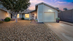 A single-story house with a garage, a driveway, and a well-maintained gravel front yard. - Summer All Year Round 2 Bedroom Home by RedAwning (Phoenix)