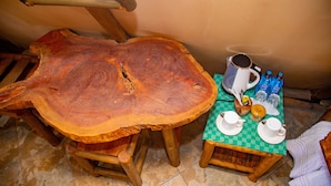 A wooden dining table with a checkered tablecloth, a coffee pot, cups, and bottled water.
