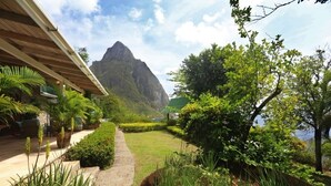 A garden pathway leading to a mountain view, surrounded by lush greenery and a building with a sloped roof. - Authentic St. Lucian Experience At Prestigious 2-bed Villa - Colibri Cottage 2 Bedroom Villa by RedAwning (Soufrière)
