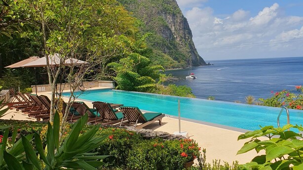 A poolside area with lounge chairs and a view of the ocean and a mountain. - Authentic St. Lucian Experience At Prestigious 2-bed Villa - Colibri Cottage 2 Bedroom Villa by RedAwning (Soufrière)
