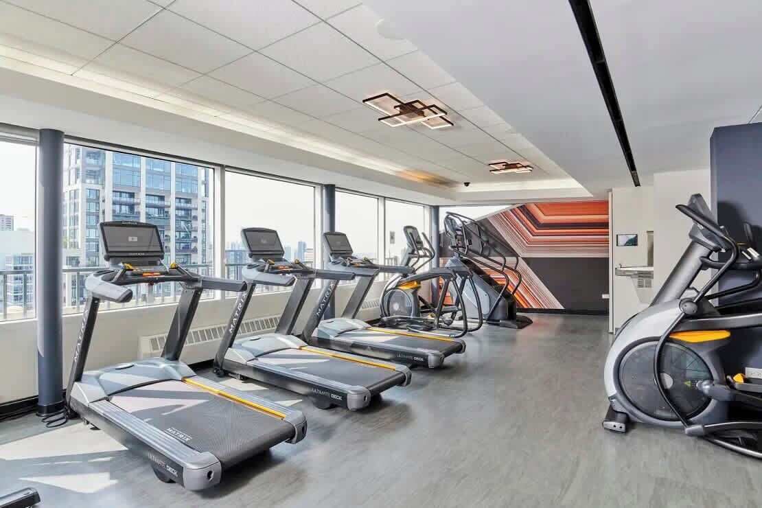 Un gimnasio moderno con cintas de correr, elípticas y una bicicleta estática.