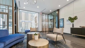 A modern lobby with a blue sofa, a beige armchair, and a round coffee table with a plant. - Luxury Designer Penthouse 3801 | Pool | Gold Coast (Chicago)