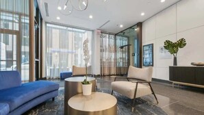 A modern lobby with a blue sofa, a beige armchair, and a round coffee table with a plant. - Luxury Designer Penthouse 3802 | Pool | Gold Coast (Chicago)