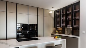 Een moderne keuken met een centraal eiland, barstoelen en een wijnrek.