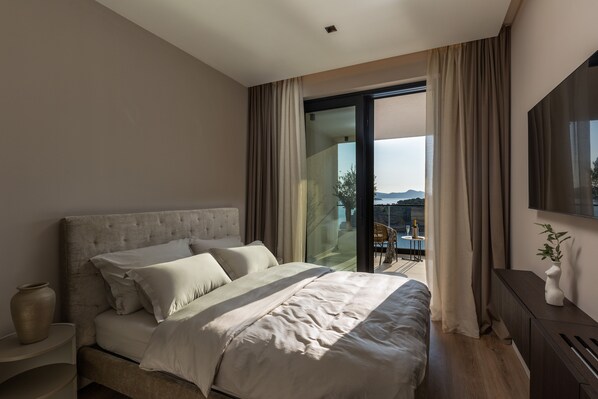 Un dormitorio moderno con una cama grande, un ventanal que da a un espacio exterior y un televisor de pantalla plana en la pared.