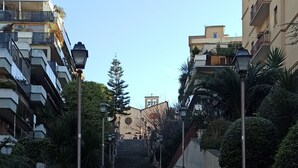 Un escalier dallé mène à un immeuble doté de nombreux balcons et d’un clocher.