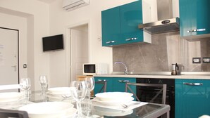 Una cocina moderna con armarios color turquesa, un microondas, una estufa y un televisor montado en la pared.