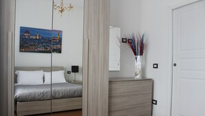 Un dormitorio con cama, cómoda, espejo y un cuadro de un paisaje urbano.