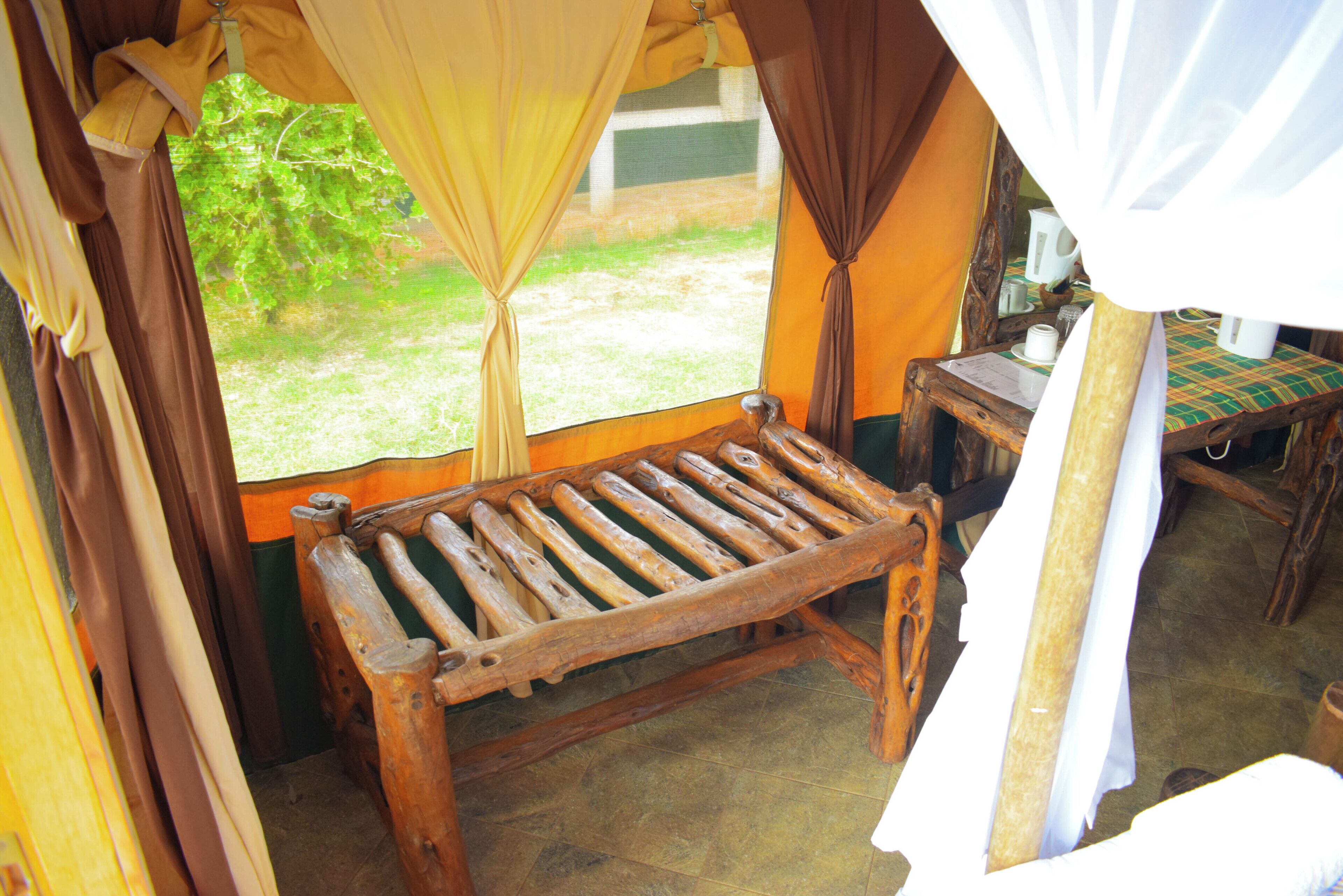 A rustic wooden bench with a view of a grassy area through a window.