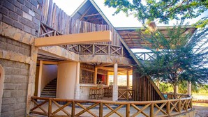 A rustic building with a stone facade, wooden balconies, and a covered outdoor seating area. - Boma Simba Lodge  (Voi)