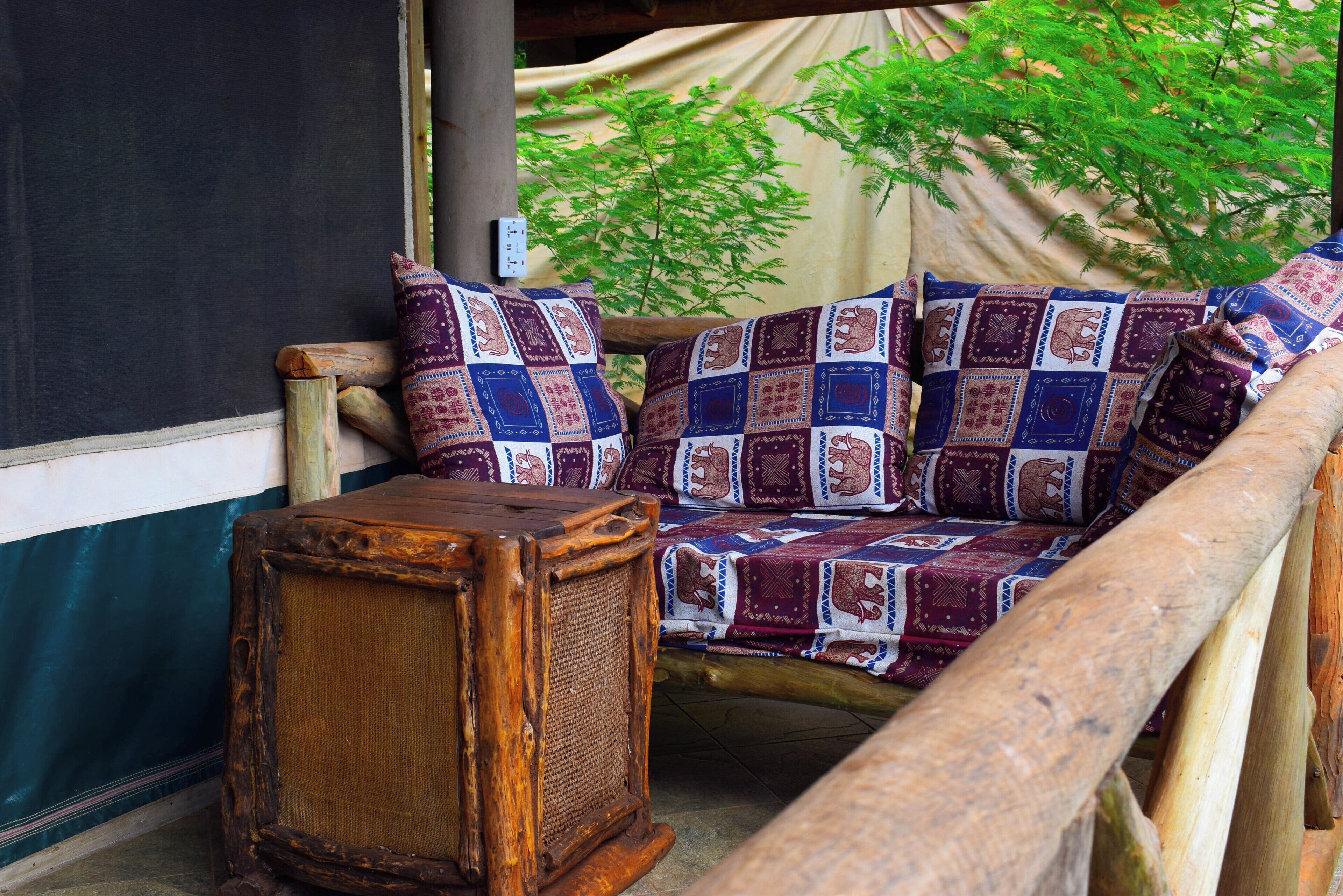 A rustic wooden bench with a woven backrest and a small wooden stool.