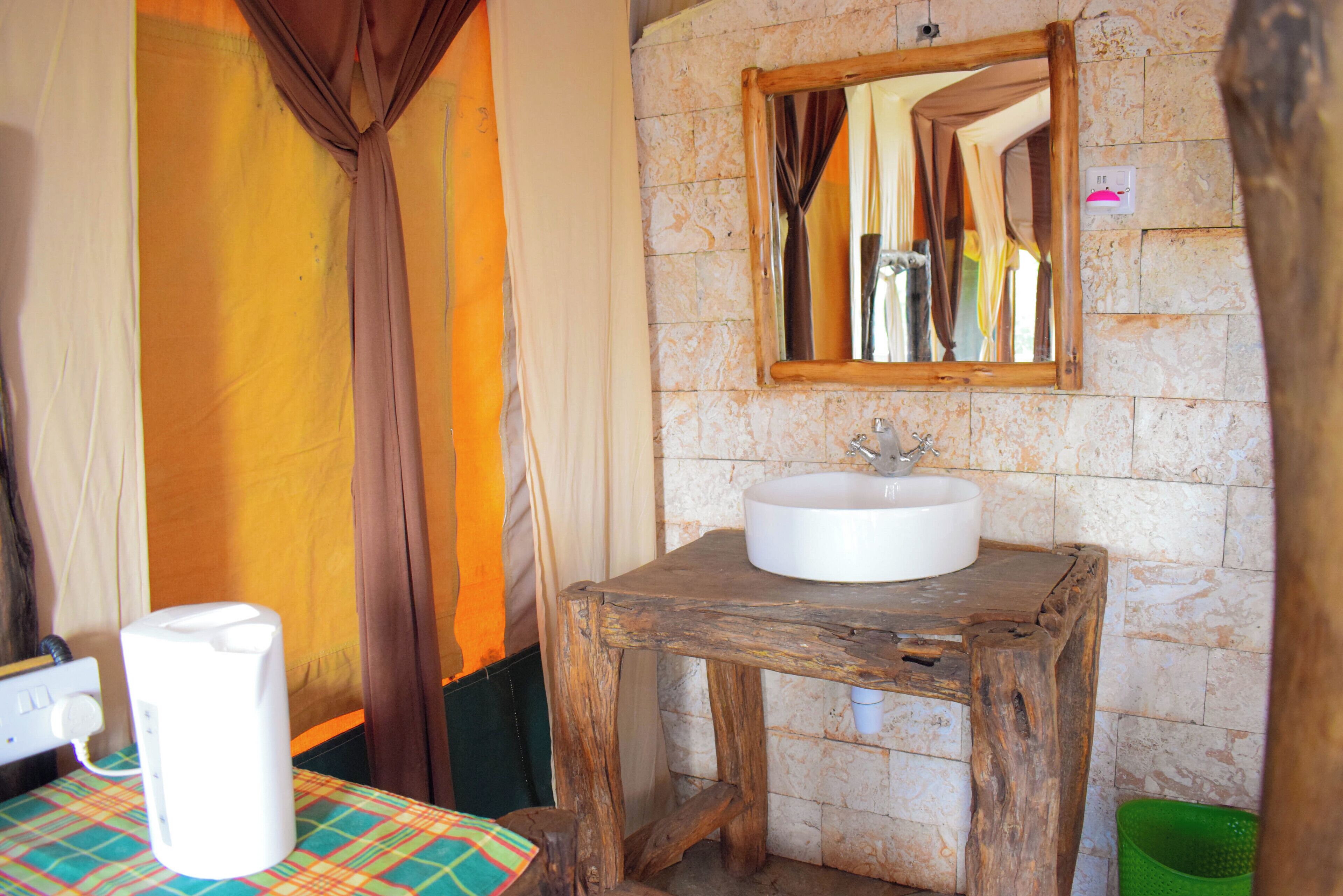 A rustic bathroom with a wooden stool, a white sink, and a mirror on the wall.