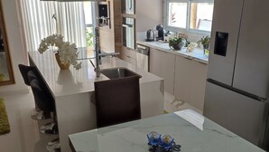 Een moderne keuken met een marmeren eiland, roestvrijstalen apparatuur en een eethoek met stoelen.