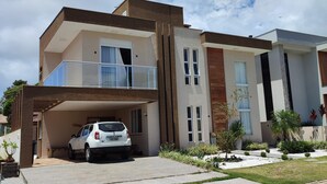 Een modern huis met twee verdiepingen, met een auto op de oprit, een overdekte garage en een verzorgde tuin.