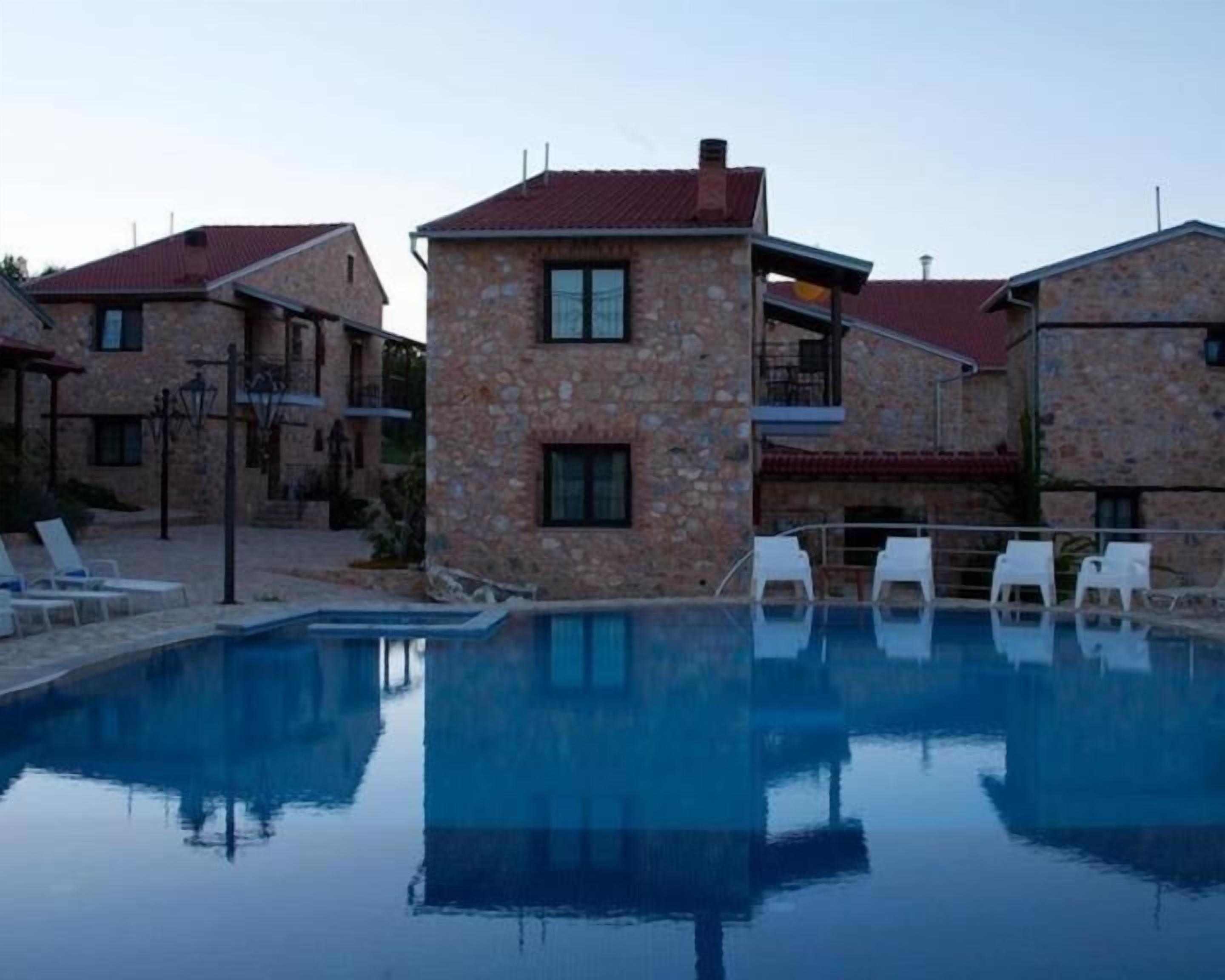 Ein Poolbereich mit Steingebäuden und weißen Liegestühlen.
