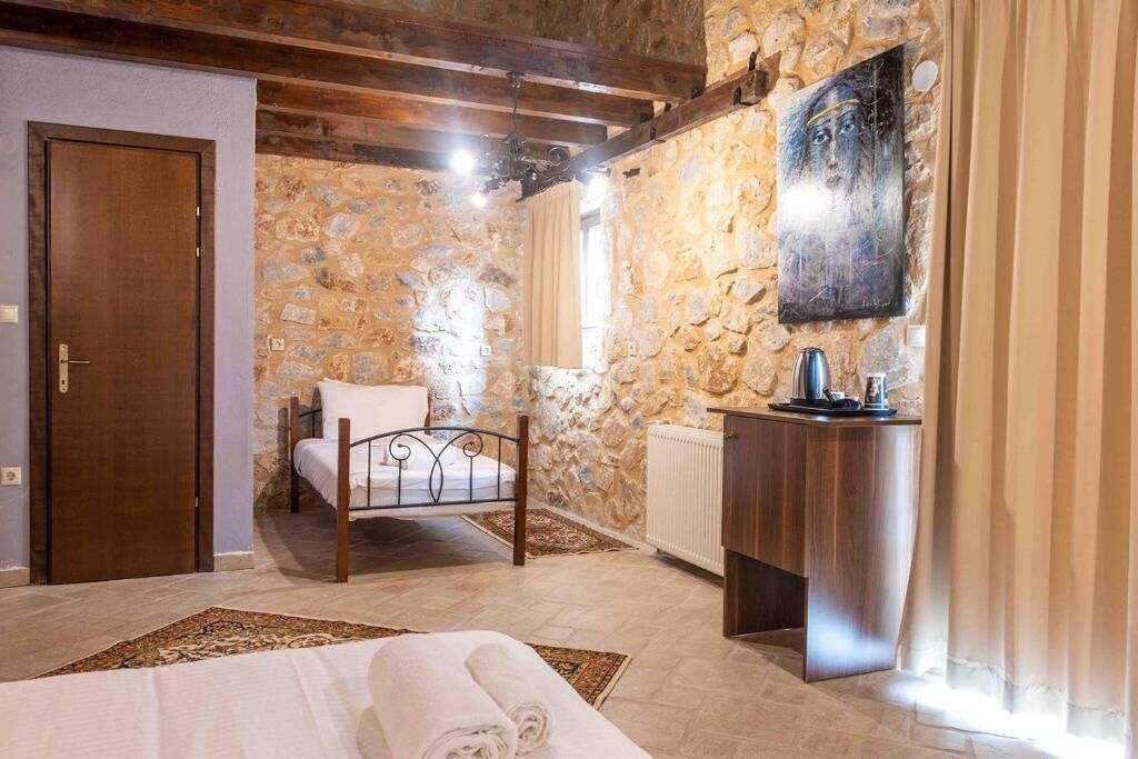 A bedroom with a stone wall, a wooden bed, a bedside table, and a radiator.