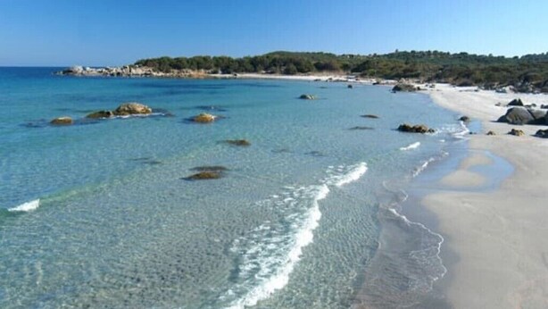 Une plage avec une eau claire, des rochers et une rive sablonneuse.