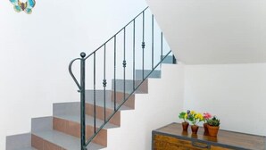 Un escalier avec des rampes en métal et une commode en bois ornée de plantes en pot.