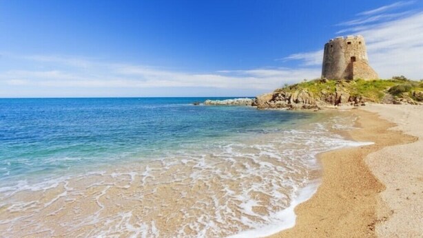 A coastal castle with a beach in the foreground.