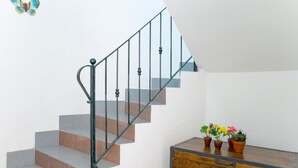 A staircase with a metal railing and a wooden chest of drawers with potted plants.