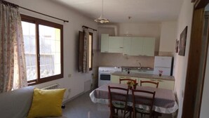 A compact living space with a kitchenette, a dining area, and a sofa with a yellow pillow.