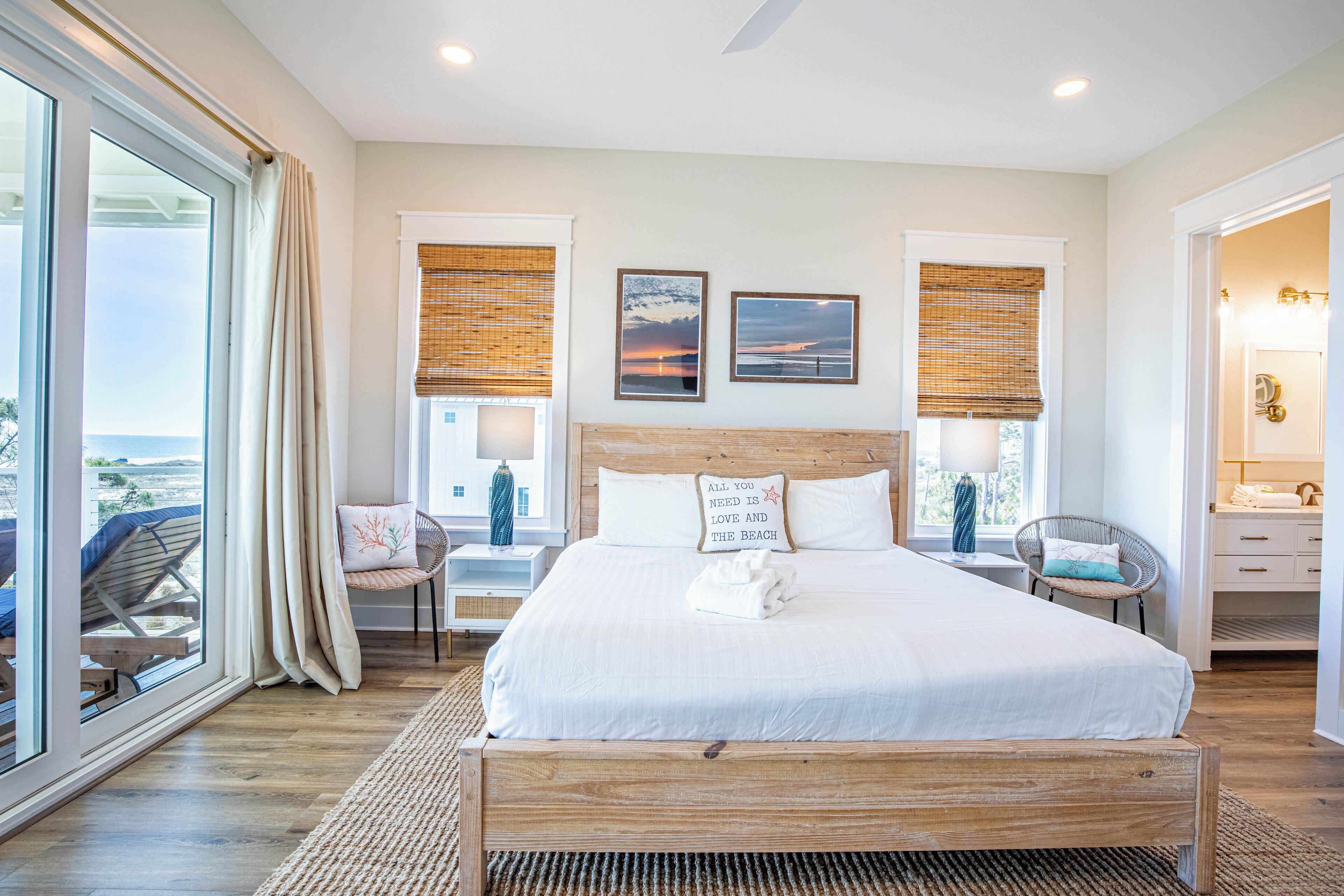 A spacious bedroom with a large bed, a view of the beach, and a balcony.
