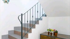 A staircase with a metal railing, wooden steps, and a wooden dresser with potted plants. - ENTIRE VACATION HOME BARI SARDO Iun.gov.it Q0005 (Bari Sardo)
